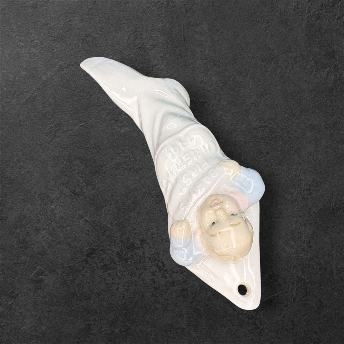Figura Lladró original de porcelana con bebé en calcetín navideño, ideal para decorar en Navidad. Pieza titulada 'La primera Navidad del bebé'.