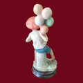 Parte trasera de figura niño con globos estilo Capodimonte, mostrando globos multicolores y acabado artesanal en resina sobre peana.
