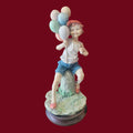 Figura niño con globos estilo Capodimonte sobre peana de madera, en resina colorida y alegre. Ideal para decoración de interiores exclusiva.