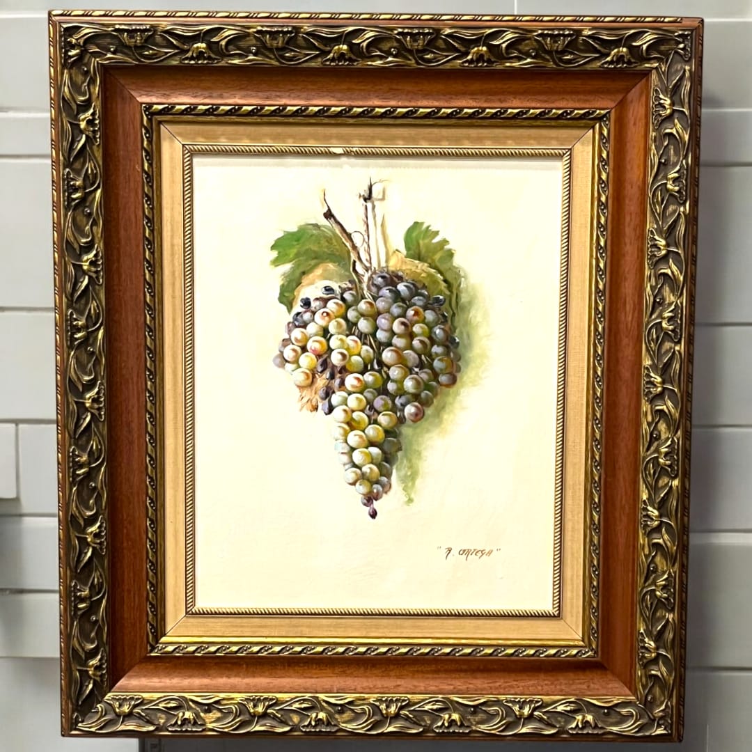 Cuadro al óleo con racimo de uvas verdes, firmado por Manuel Ruiz Ortega. Marco ornamentado ideal para decoración sofisticada del hogar.