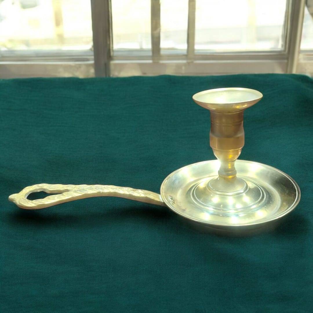 Palmatoria de metal dorado con diseño clásico y mango calado grabado. Ideal como portavela decorativo en ambientes tradicionales.