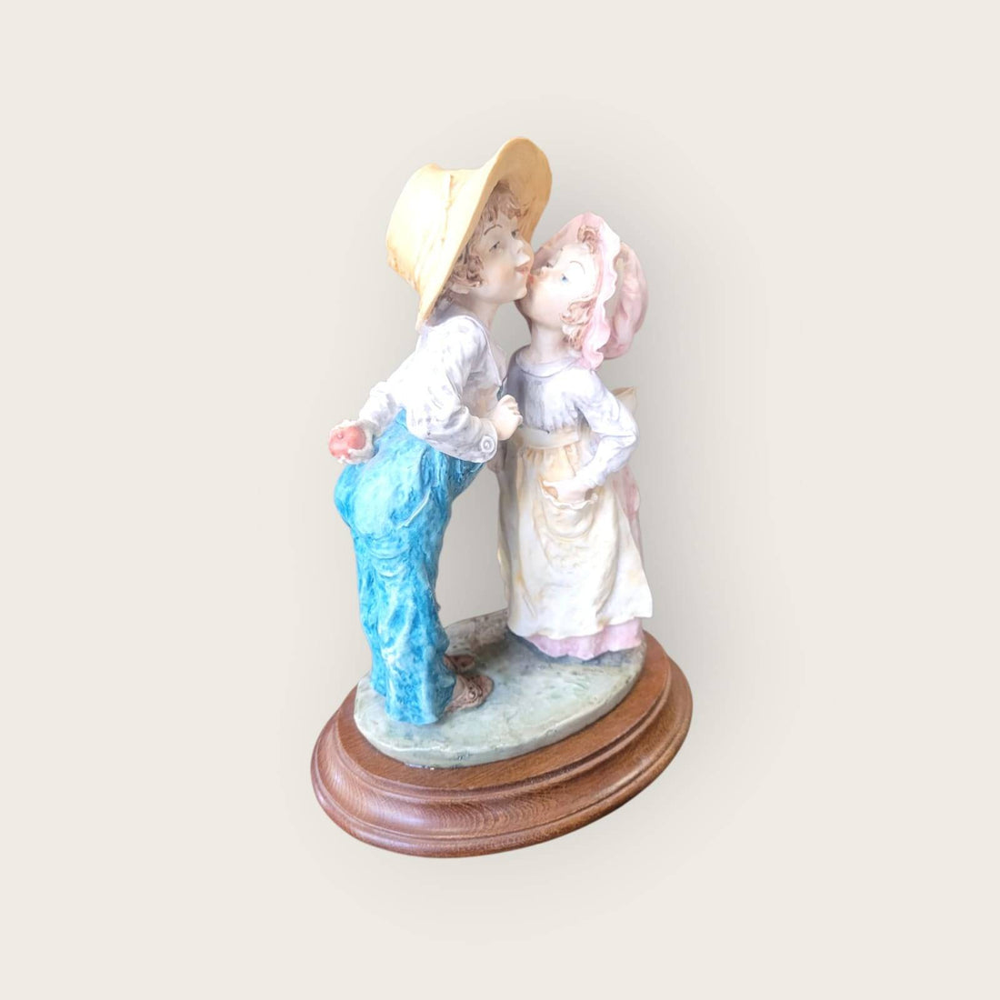 Figura Beso Tímido Resina - Romántica sobre base de madera, muestra a una pareja infantil en gesto de beso, ideal para decoración del hogar.