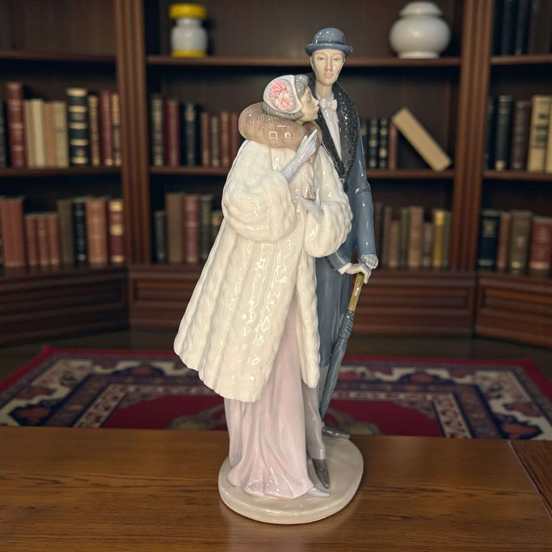 La Pareja Lladró representa a una pareja paseando, vestida con indumentaria clásica, modelada con una suavidad impecable y acabados brillantes que reflejan la luz con sutileza.