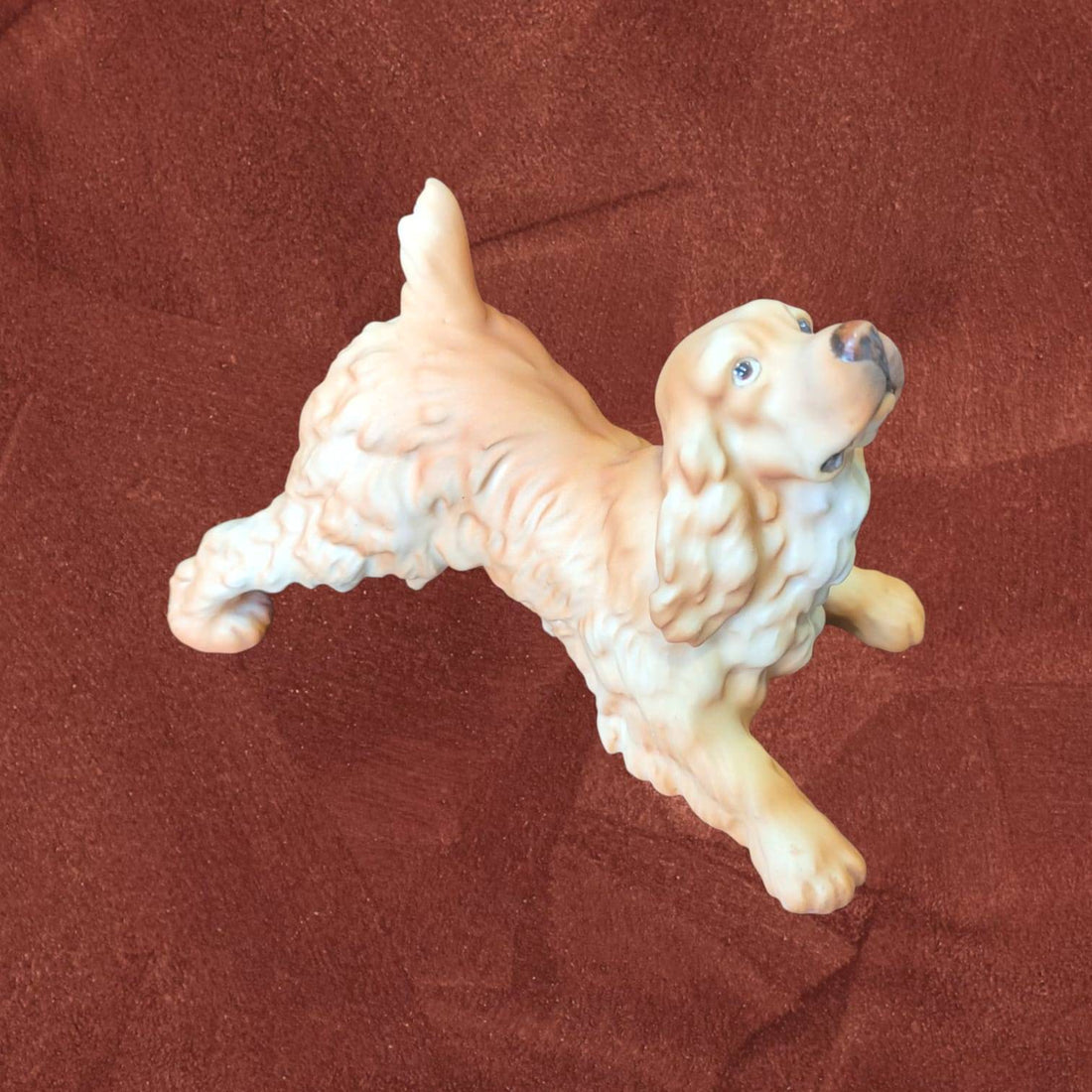 Figura Cocker Spaniel biscuit firmada por C. Martinus en pose juguetona, escultura sin esmalte ideal para decoración y coleccionistas de perros.