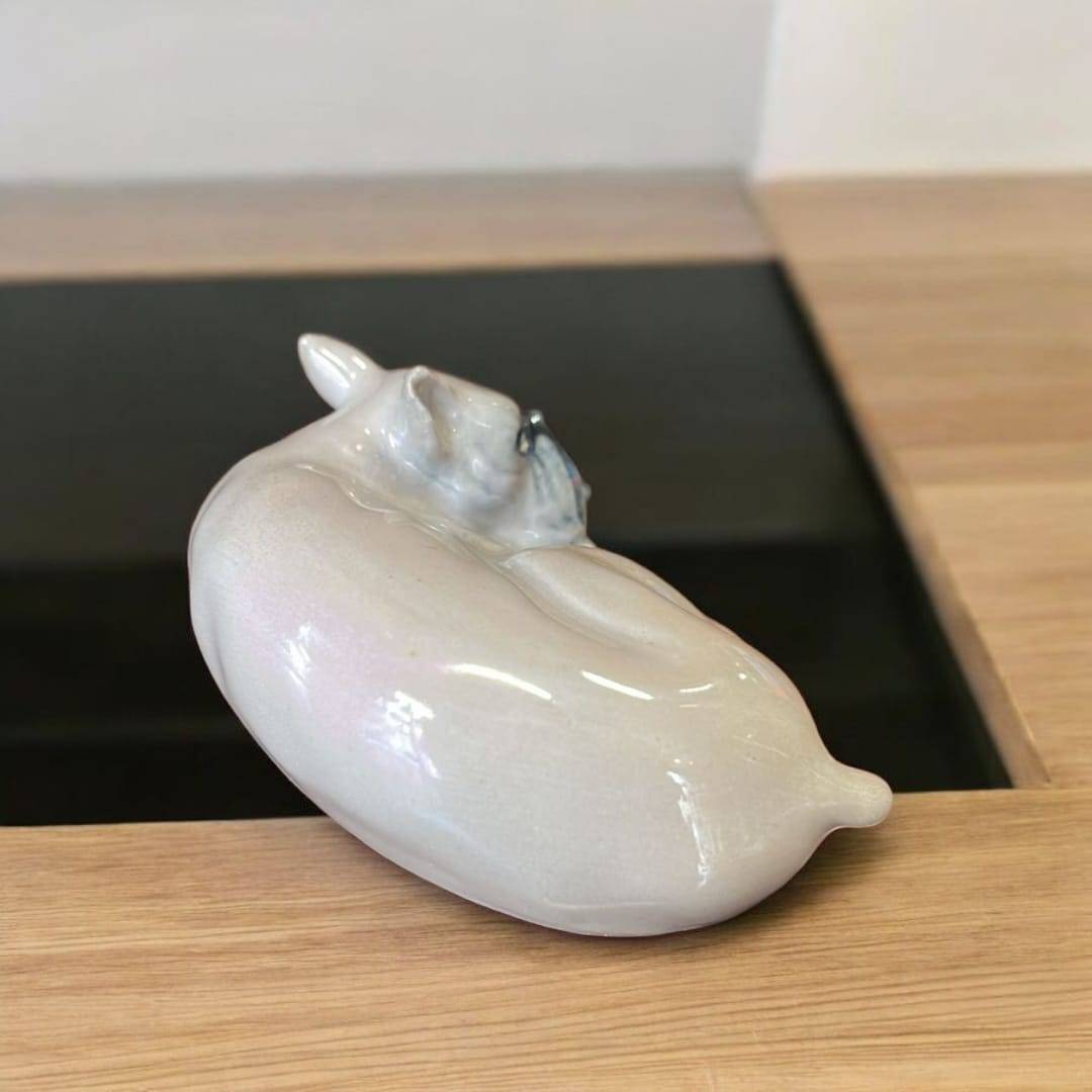 Vista trasera de escultura de Boxer dormido en porcelana vidriada de Leonardo PEYRO, colocada sobre mesa de madera. Arte decorativo para el hogar.