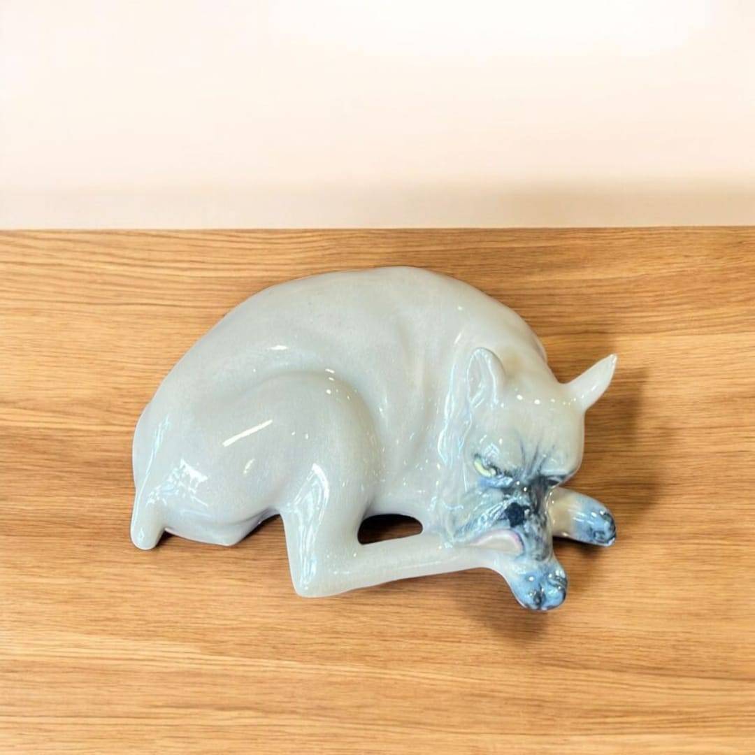 Escultura de porcelana Leonardo PEYRO de un Boxer dormido, con acabado vidriado brillante, sobre superficie de madera. Decoración elegante para hogar.
