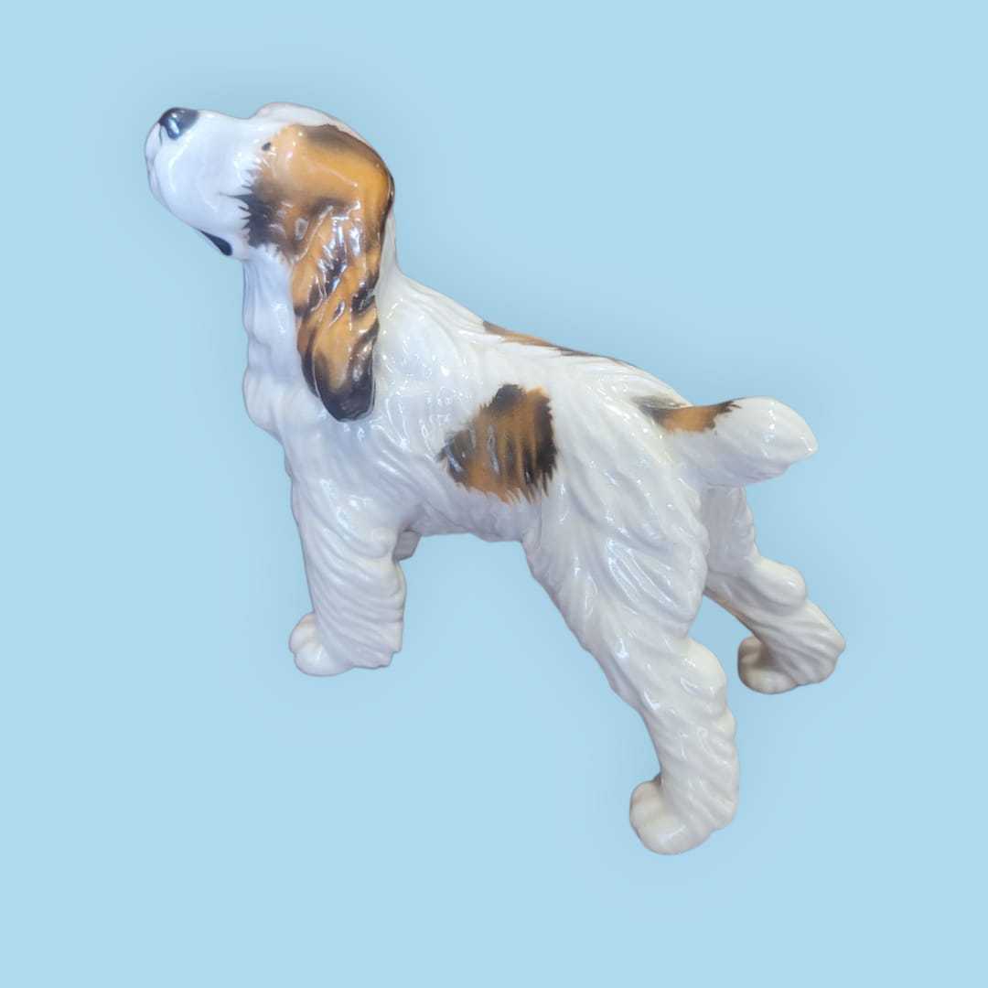 Figura decorativa de porcelana alemana años 50, perro Cocker con acabado brillante y detalles pintados a mano en tonos naturales.