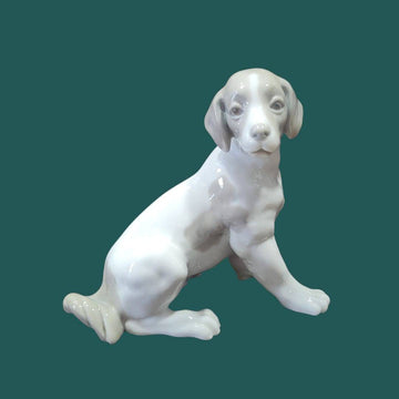 Figura perro NAO Lladró - Porcelana Cachorro Sentado con acabado brillante, ideal para decoración de interiores o colección artística.