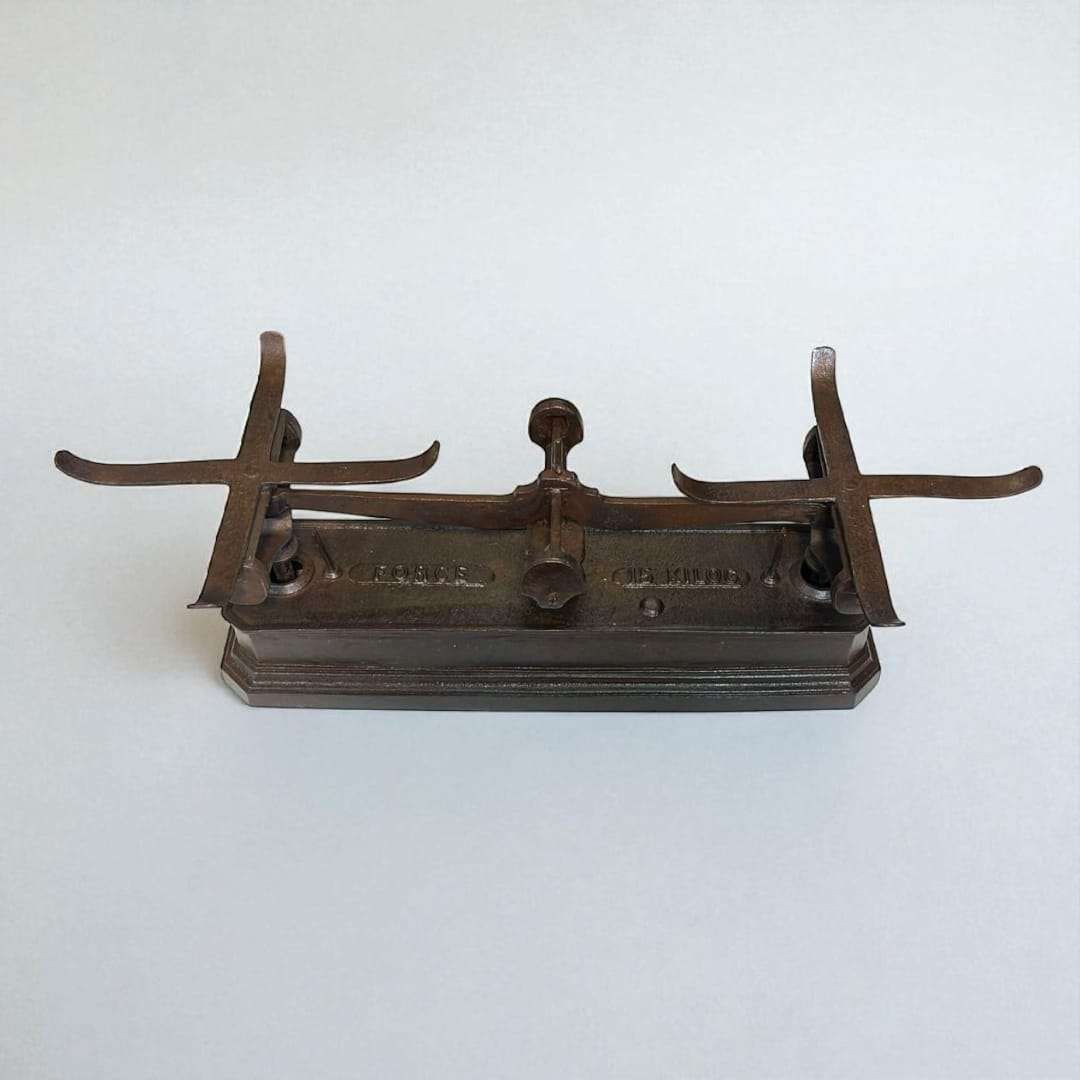 Balanza de hierro con platos metálicos sobre mesa de madera.