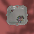 Vista lateral de bandeja de porcelana con relieve y perforaciones decorativas.