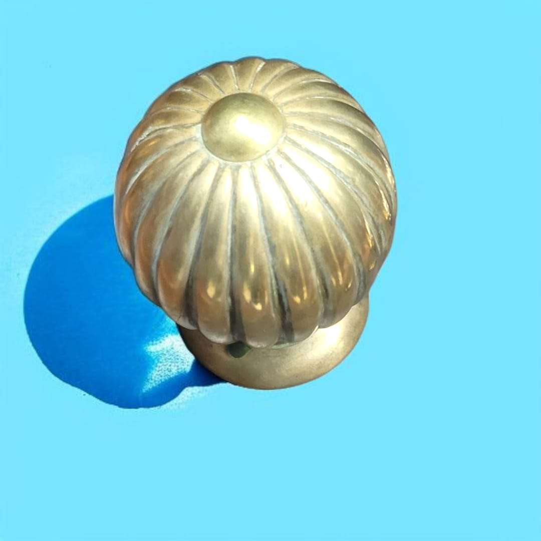 Pomo o remate decorativo de bronce sobre madera barnizada