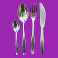 Detalle de cubiertos de metal plateado con diseño clásico: cuchara, tenedor, cuchillo y cucharilla, perfectos para decoración refinada.