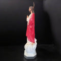 Vista lateral de la figura Sagrado Corazón de Jesús majestuosa y religiosa, mostrando detalles del manto rojo y postura bendiciente.