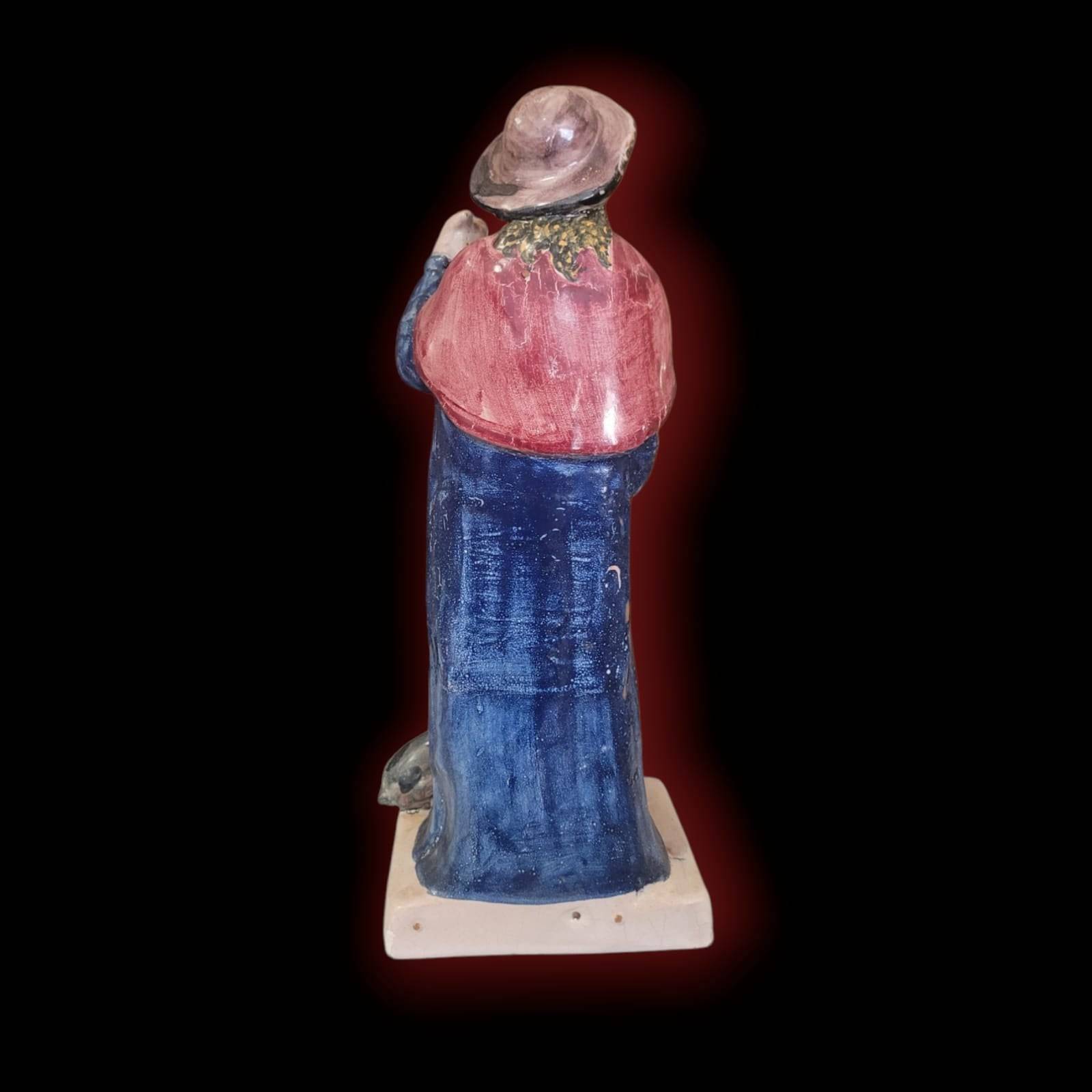 Parte trasera de la figura San Roque de terracota esmaltada, con capa roja y sombrero. Objeto decorativo único para coleccionistas religiosos.
