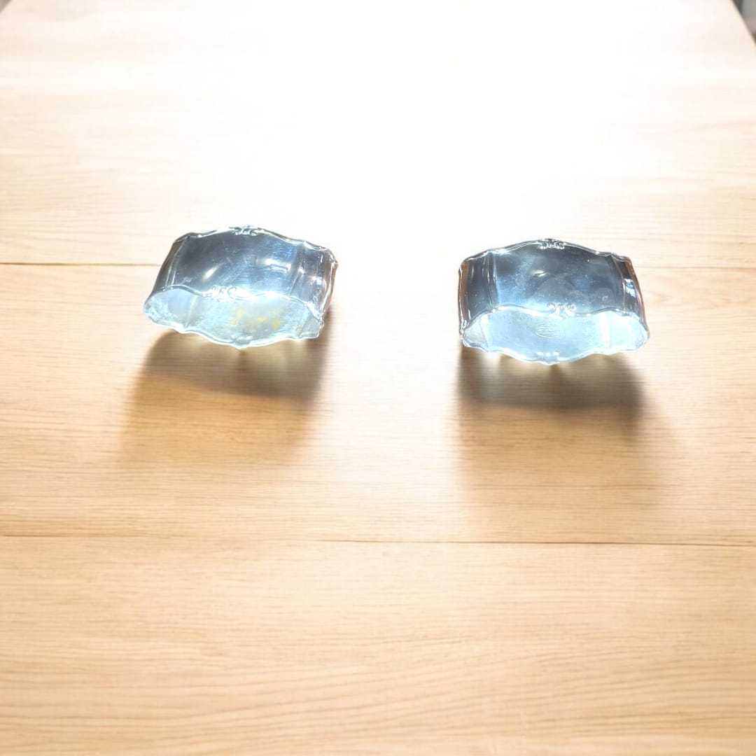 Servilleteros de metal plateado con diseño elegante sobre mesa de madera clara. Decoración clásica para mesas sofisticadas en el hogar.