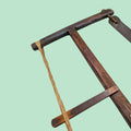Detalle del marco y cuerda de la sierra de arco manual antigua de madera, ideal como elemento decorativo en espacios rústicos o vintage.