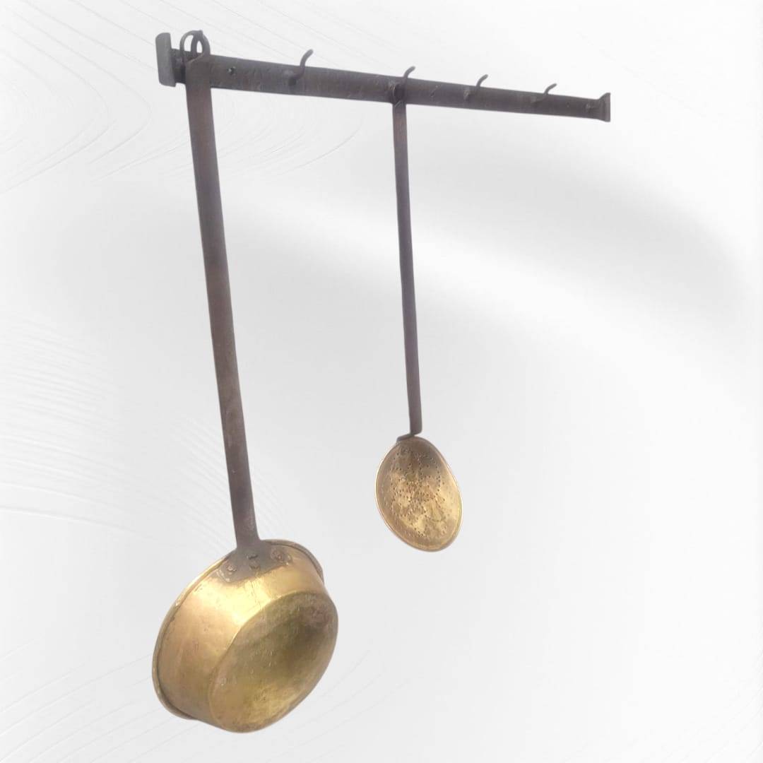 Soporte de forja antigua instalado con cucharones colgantes, perfecto para decoración de cocina estilo rústico o tradicional.