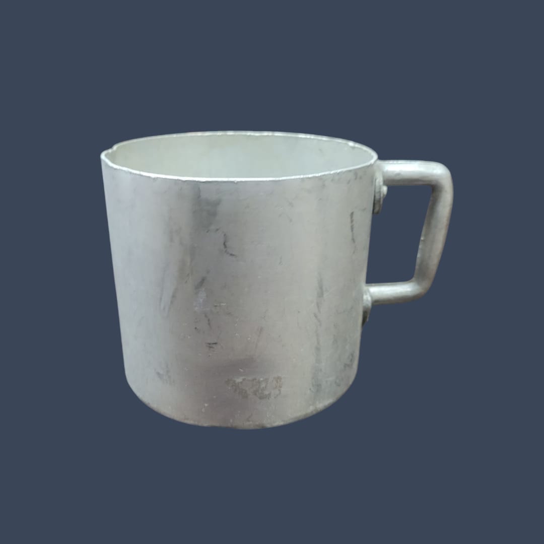 Persona sosteniendo la taza de aluminio mientras disfruta de una bebida caliente al aire libre.