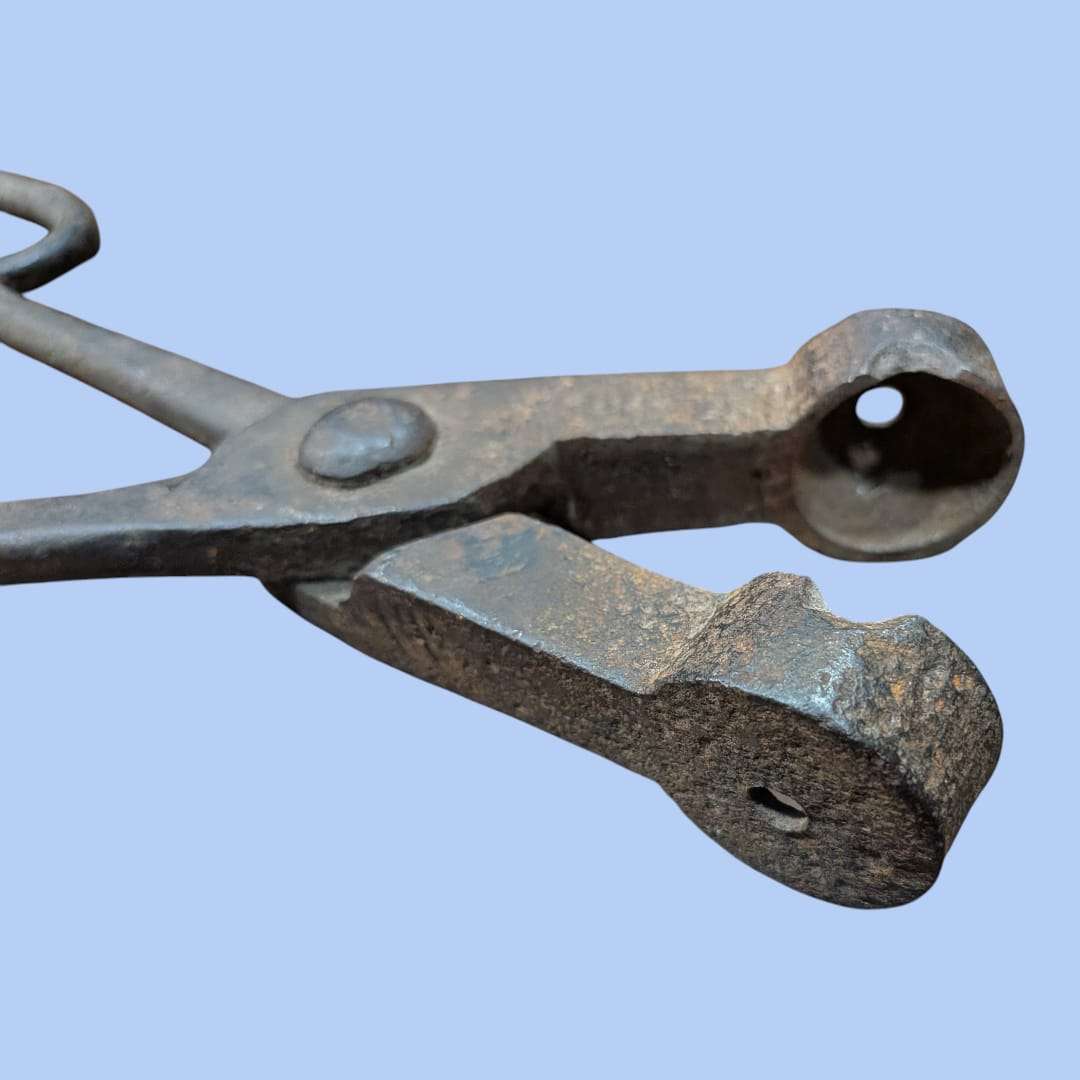 Alicates antiguos para hacer bolas de rejas de hierro en primer plano, herramienta de forja artesanal con acabado envejecido, ideal para decoración industrial.