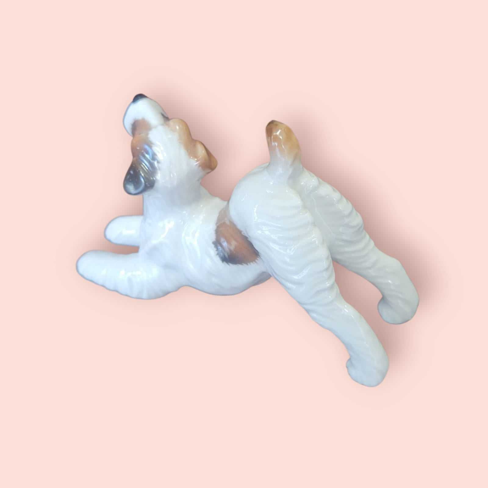 Figura de perro FOX TERRIER en porcelana alemana vintage, años 50, vista en ángulo mostrando orejas caídas y esmaltado artesanal.