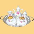 Juego de café 'Tú y Yo' con diseño floral en porcelana fina, detalles dorados y bandeja plateada para momentos especiales.