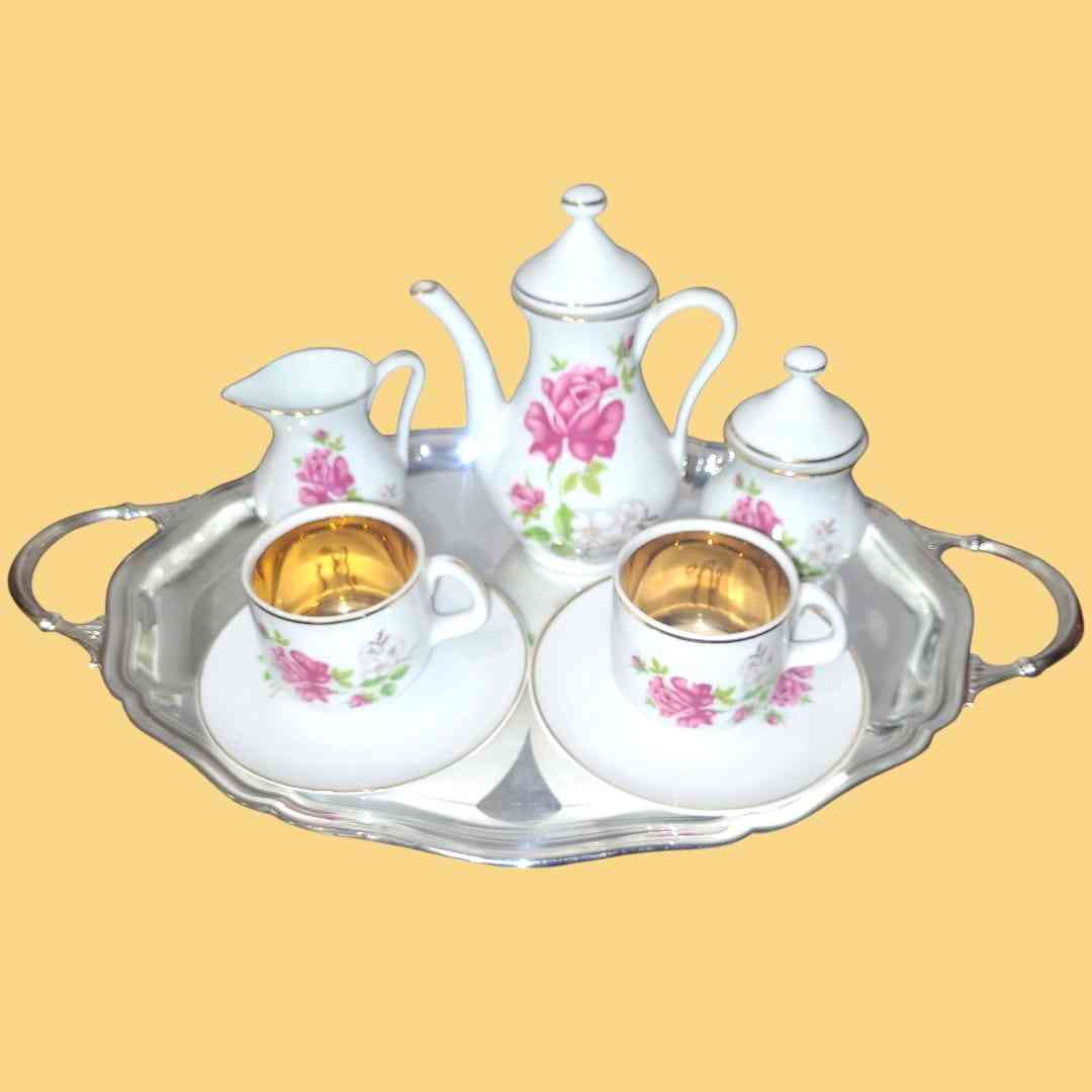 Juego de café 'Tú y Yo' con diseño floral en porcelana fina, detalles dorados y bandeja plateada para momentos especiales.