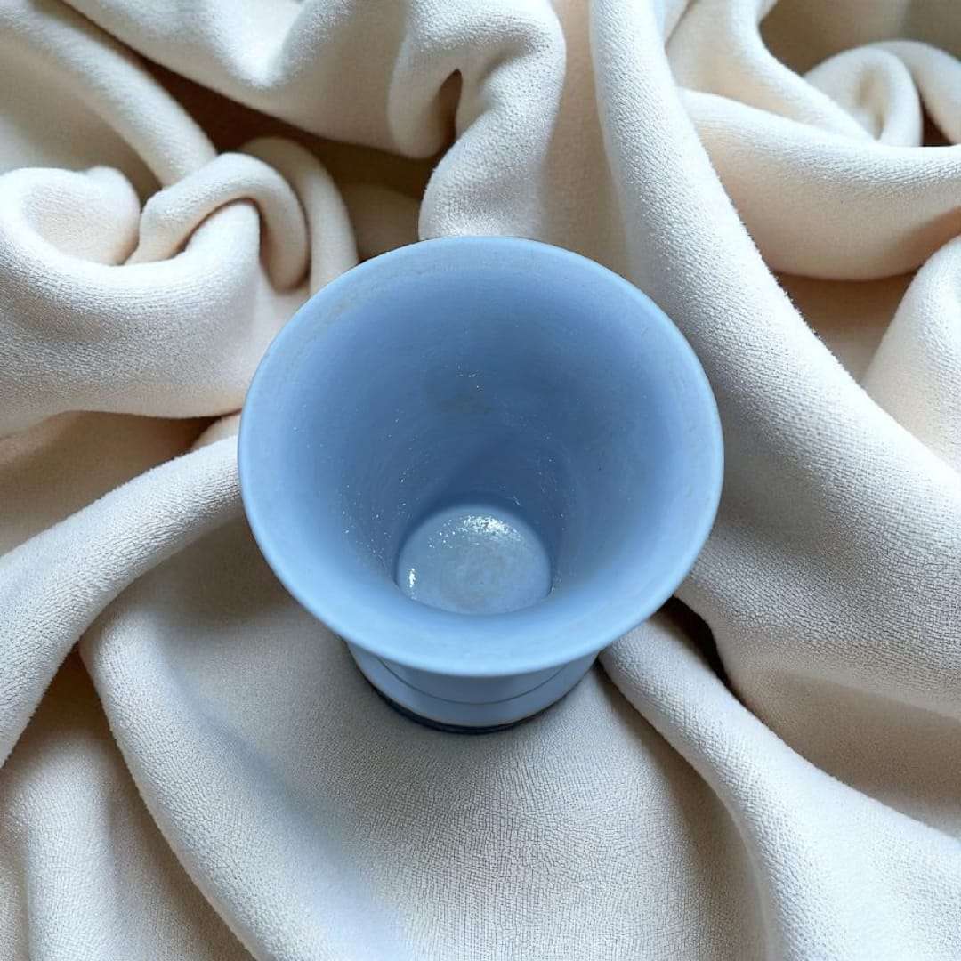 Vista superior del jarrón Wedgwood azul jaspeado con relieve estilo clásico único, mostrando su interior cerámico sobre tela suave.