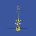 Velón de metal dorado con estructura vertical y detalles curvos, ideal para decoración de interiores en estilo clásico o espiritual. Base estable y diseño refinado.