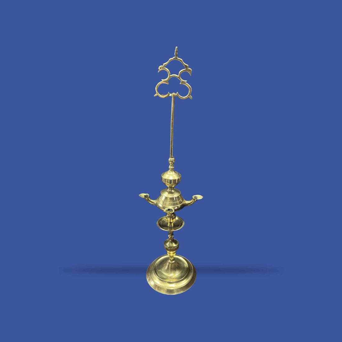 Velón de metal dorado con estructura alta y decorativa, ideal para decoración clásica en interiores solemnes. Diseño vertical con base amplia y detalles ornamentales.