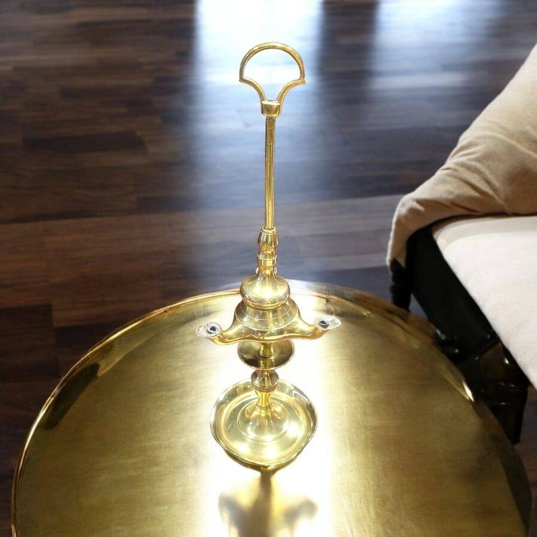 Velón de aceite vintage de 3 brazos en metal dorado sobre mesa decorativa, perfecto para ambientes clásicos y sofisticados.