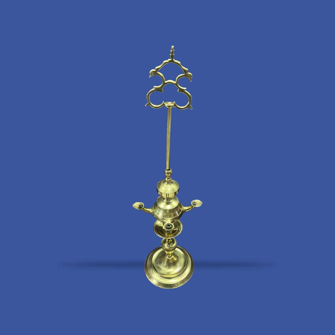 Velón de metal dorado con estructura alta y decorativa, ideal para decoración clásica en interiores solemnes. Diseño vertical con base amplia y detalles ornamentales.