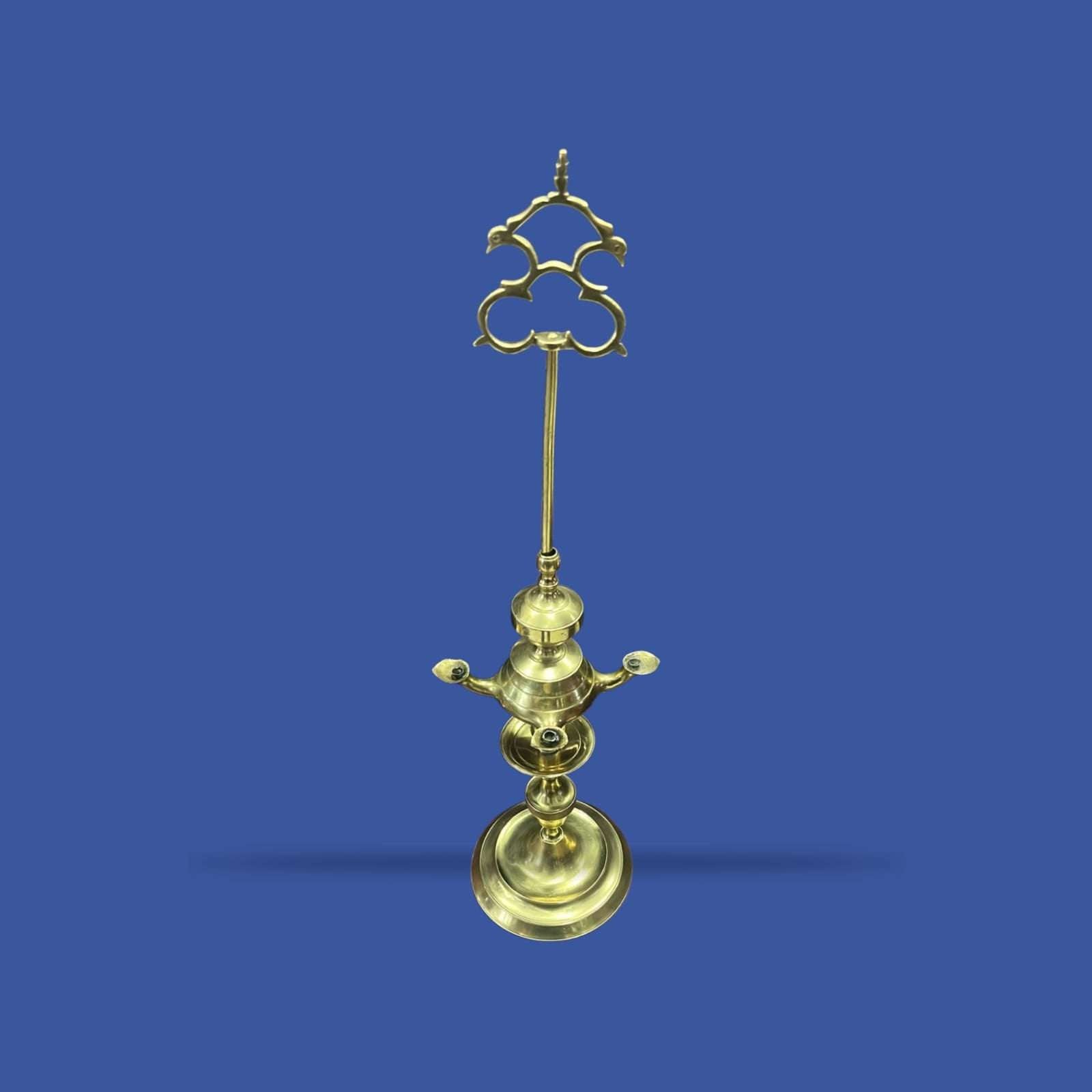 Velón dorado de metal con diseño alto y simétrico, perfecto para rituales o espacios elegantes. Su estructura decorativa aporta un toque tradicional.