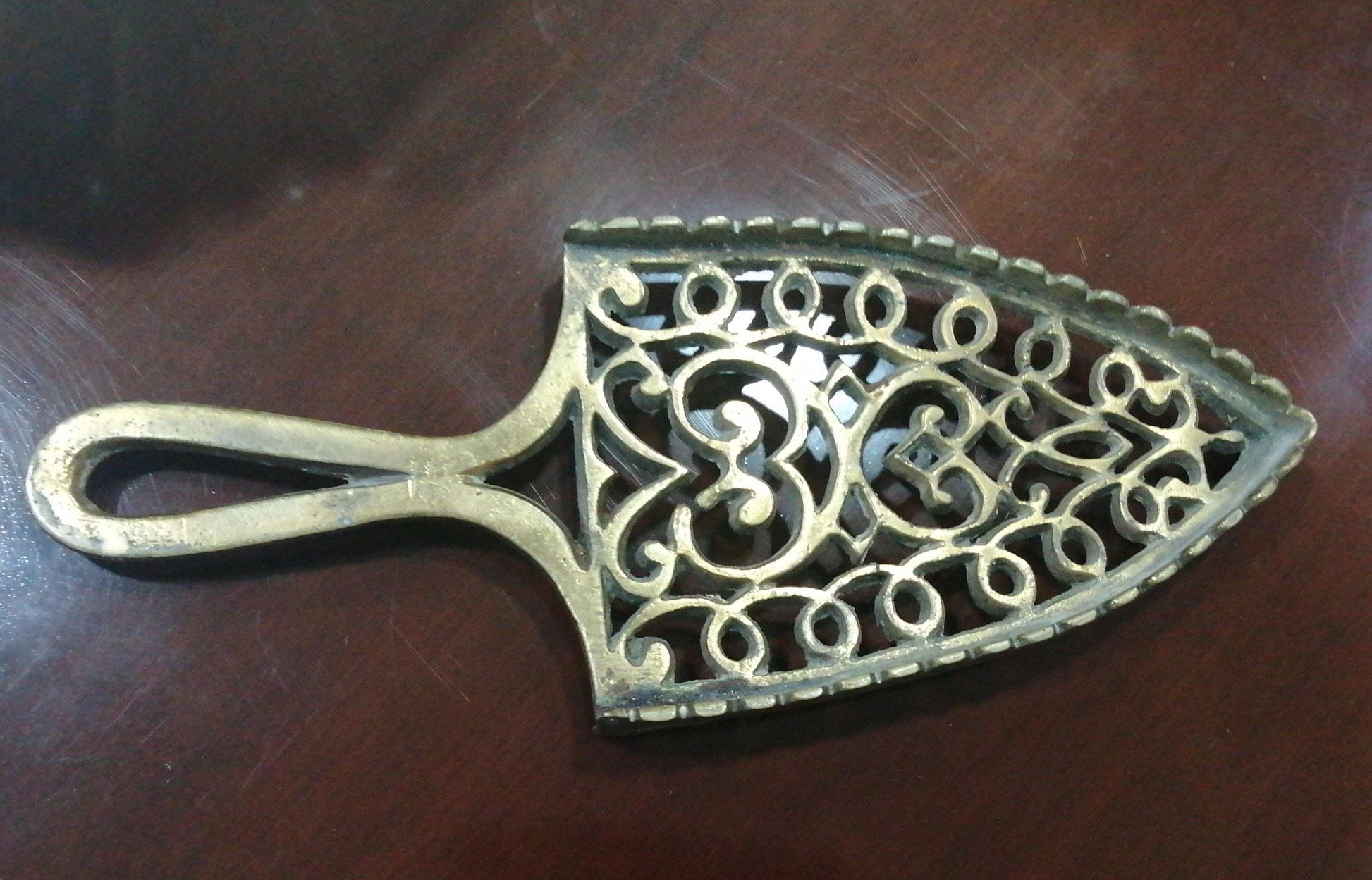 Descansadero Plancha Bronce con diseño calado vintage, ideal para decorar el hogar con estilo clásico. Pieza decorativa de metal en perfecto estado.