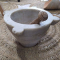 Mortero de mármol blanco antiguo con detalles tallados y mazo de madera, perfecto para decoración de interiores con estilo tradicional.