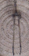 Pinza de chimenea en bronce con diseño ornamental antiguo sobre fondo de mimbre. Decoración elegante para interiores clásicos.