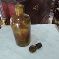 Frasco de farmacia antiguo de vidrio ámbar de 27 cm con tapa removible, perfecto para ambientaciones vintage y uso decorativo.