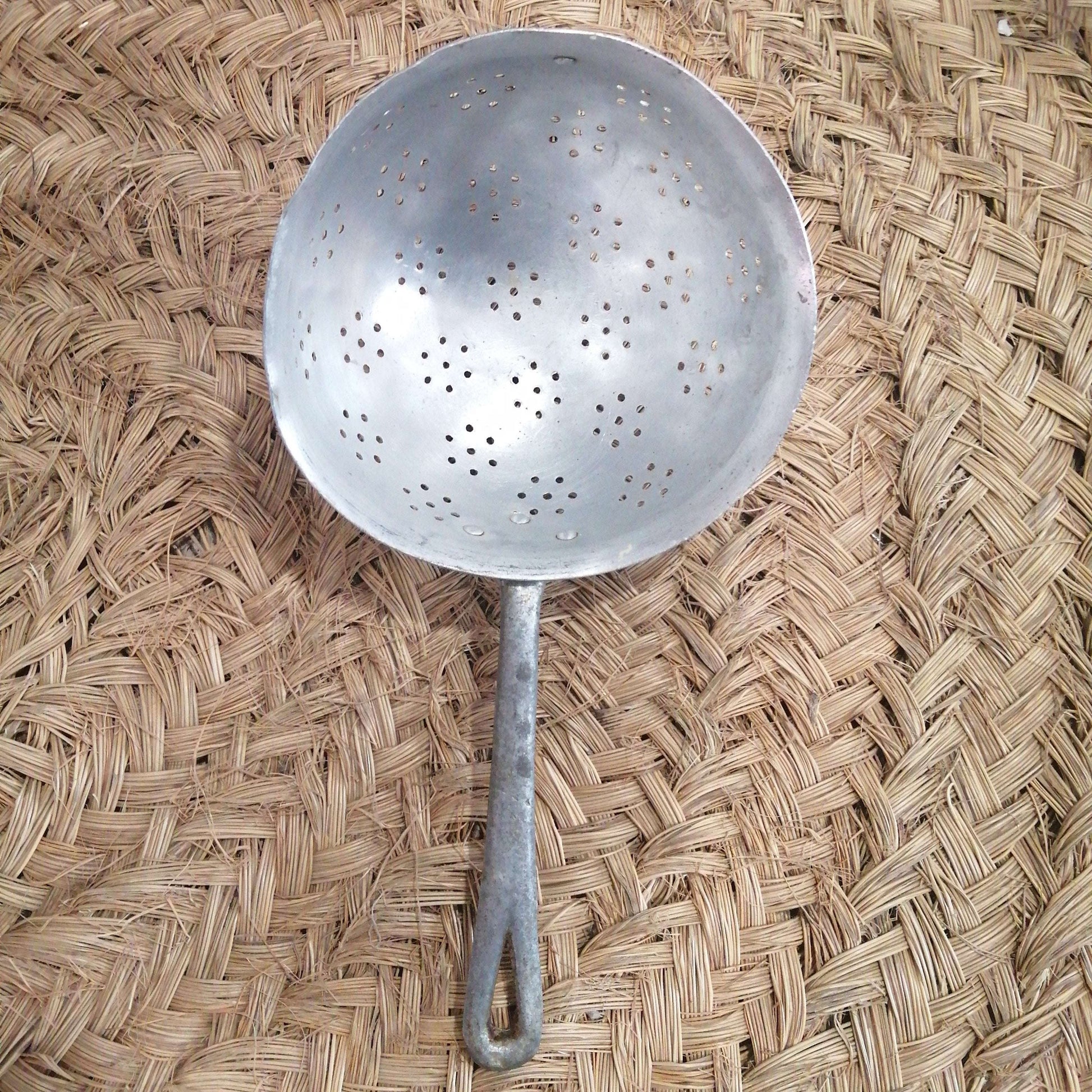Escurridor de aluminio antiguo en perfecto estado con mango largo, ideal para decoración vintage en cocina rústica o uso funcional diario.