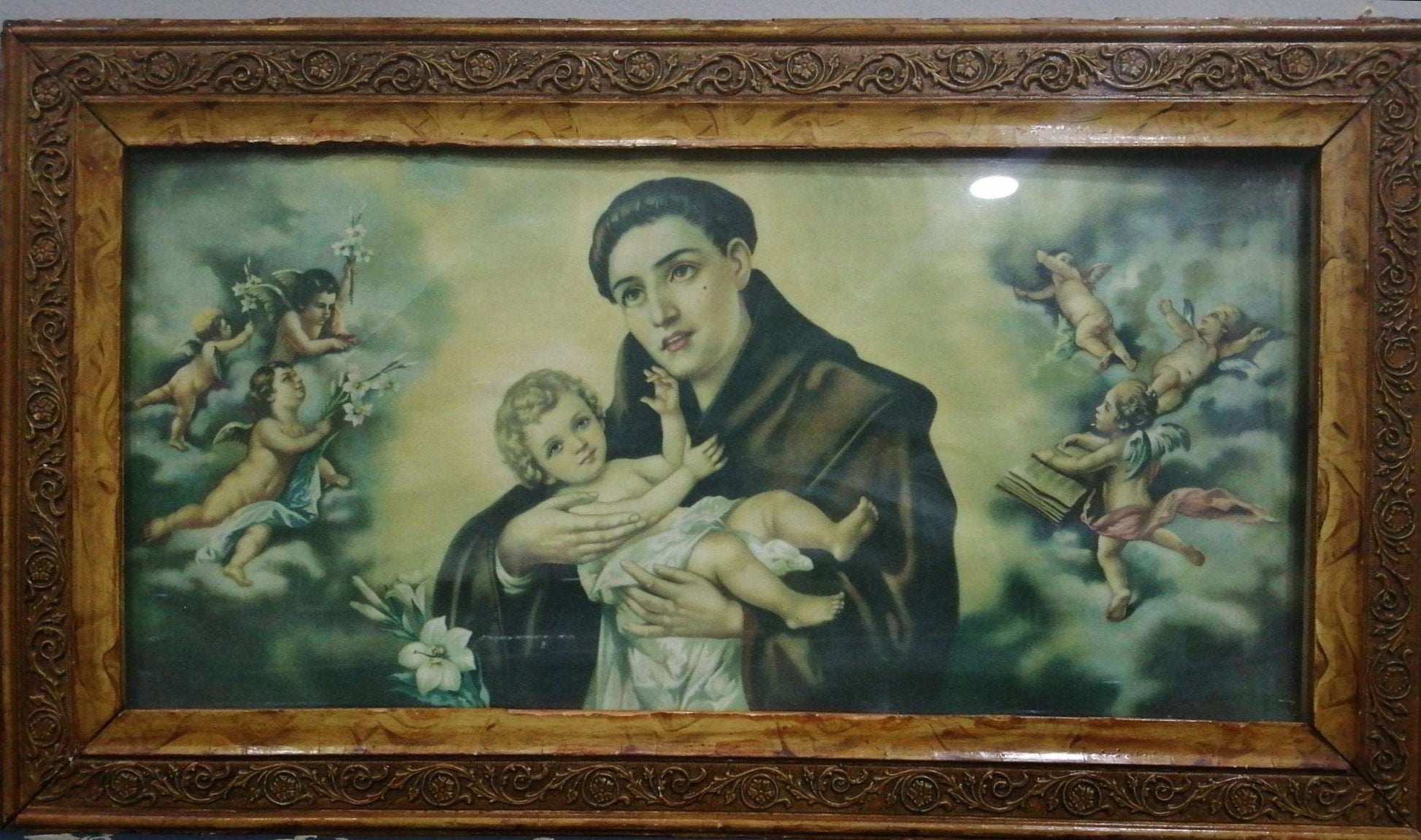 Lamina antigua de San Antonio con marco de caoba, ideal para decoración clásica del hogar. Representación religiosa con querubines en fondo celestial.