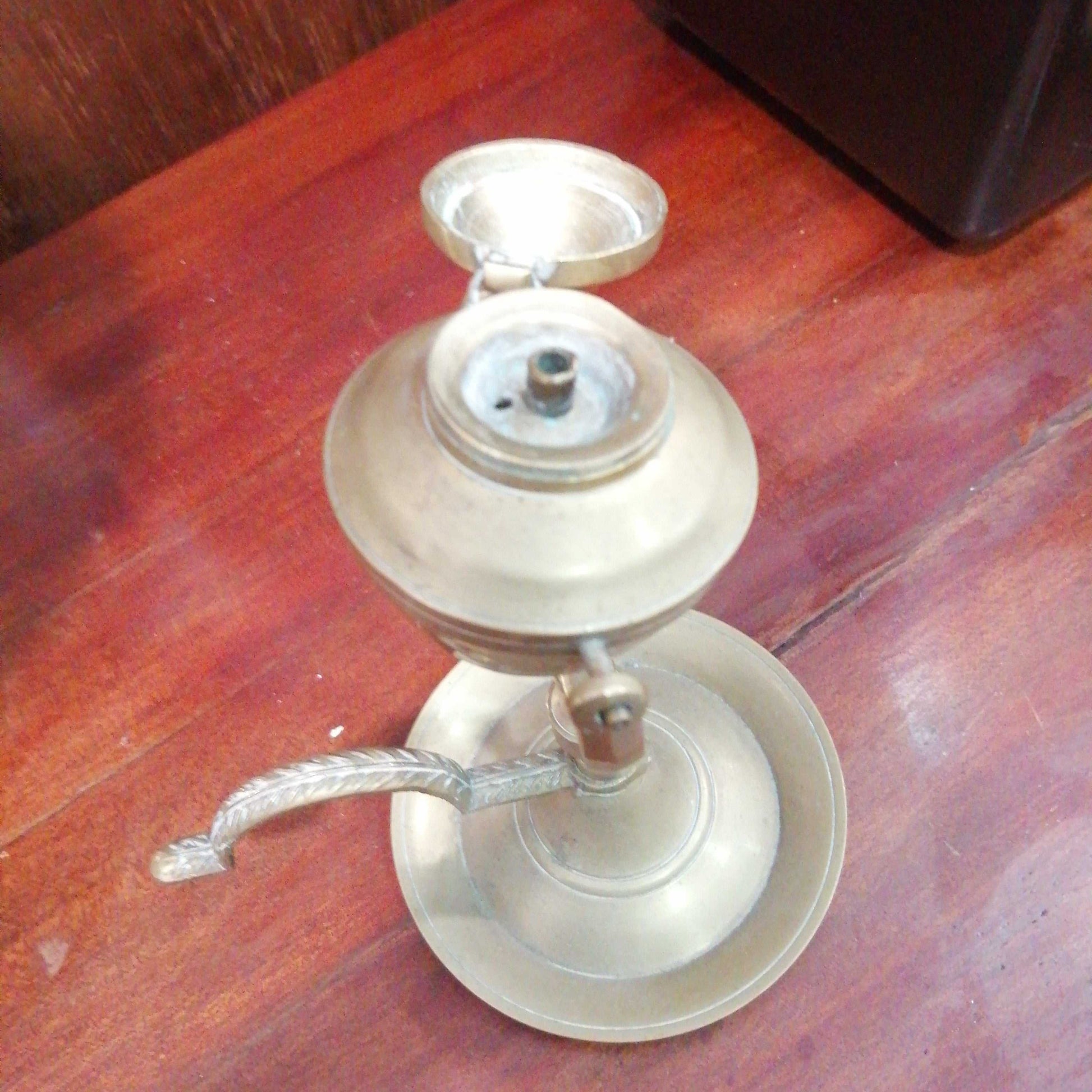 Candil antiguo de aceite en metal basculante de 17 cm sobre mesa de madera. Decoración vintage ideal para coleccionistas y espacios rústicos.