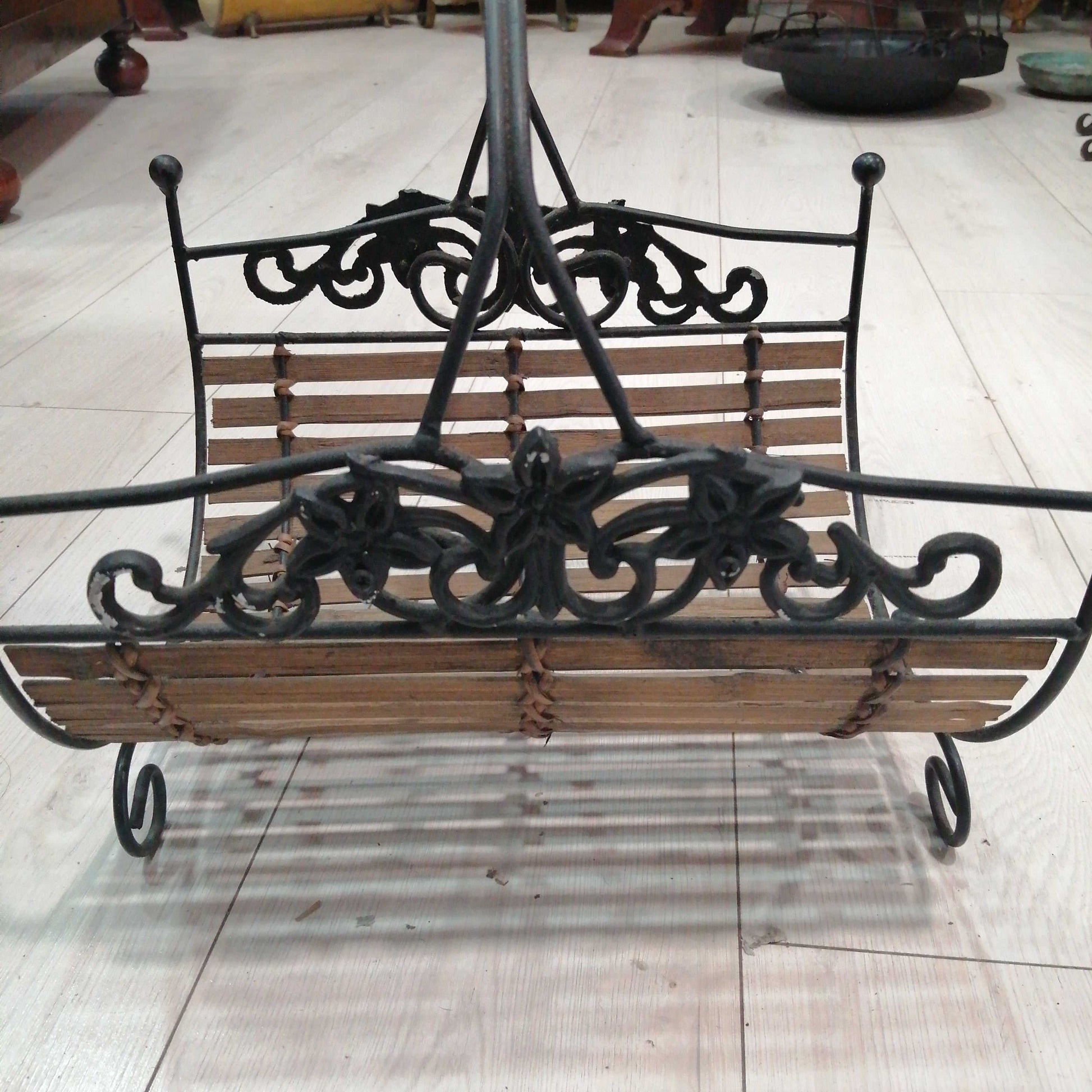 Revistero de forja con detalles ornamentales y base de madera, ideal para decoración rústica en el hogar. Calidad excepcional en cada detalle.