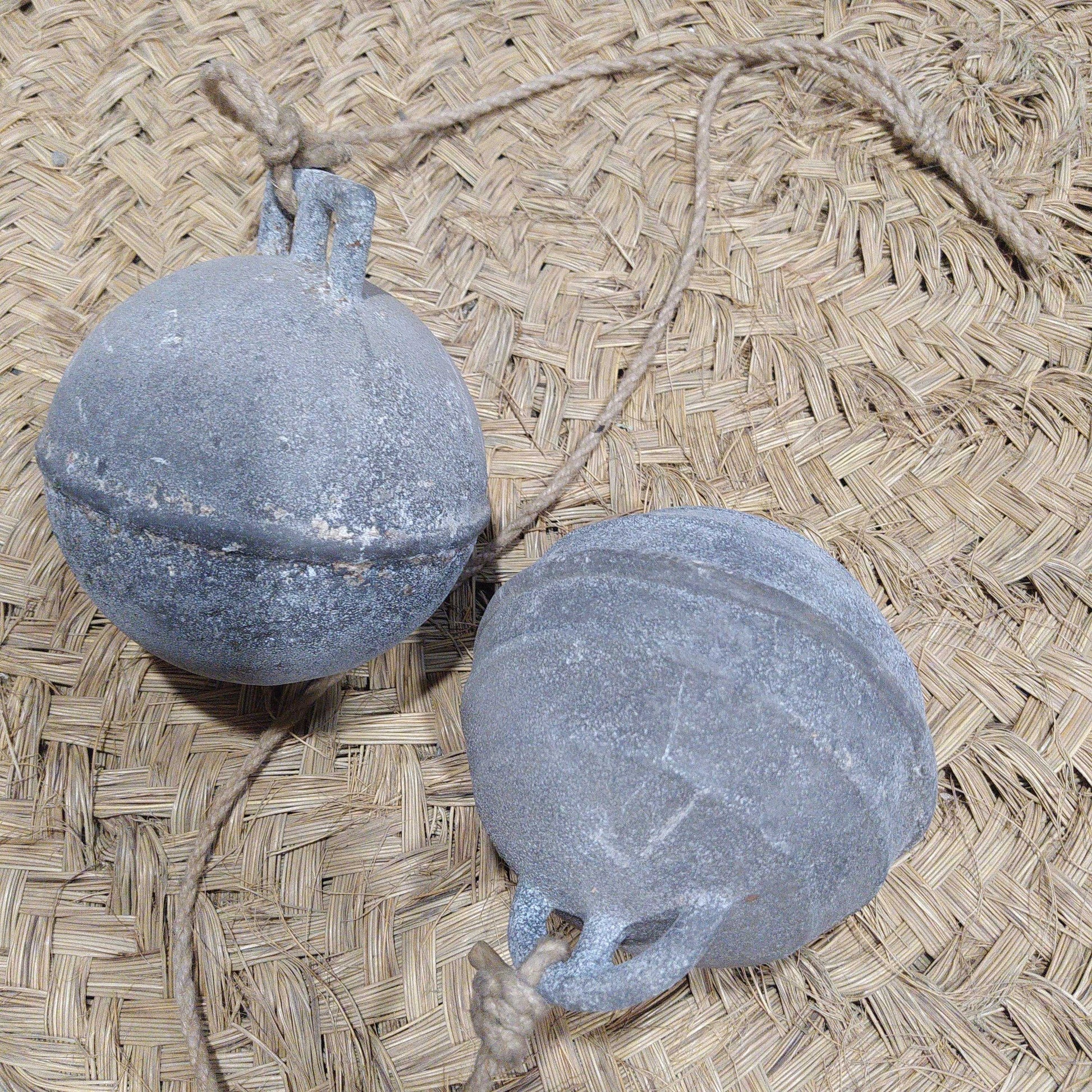 Boyas Náuticas de Calamina con acabado envejecido sobre fondo de fibra natural, ideales para decoración náutica vintage en hogar o jardín.