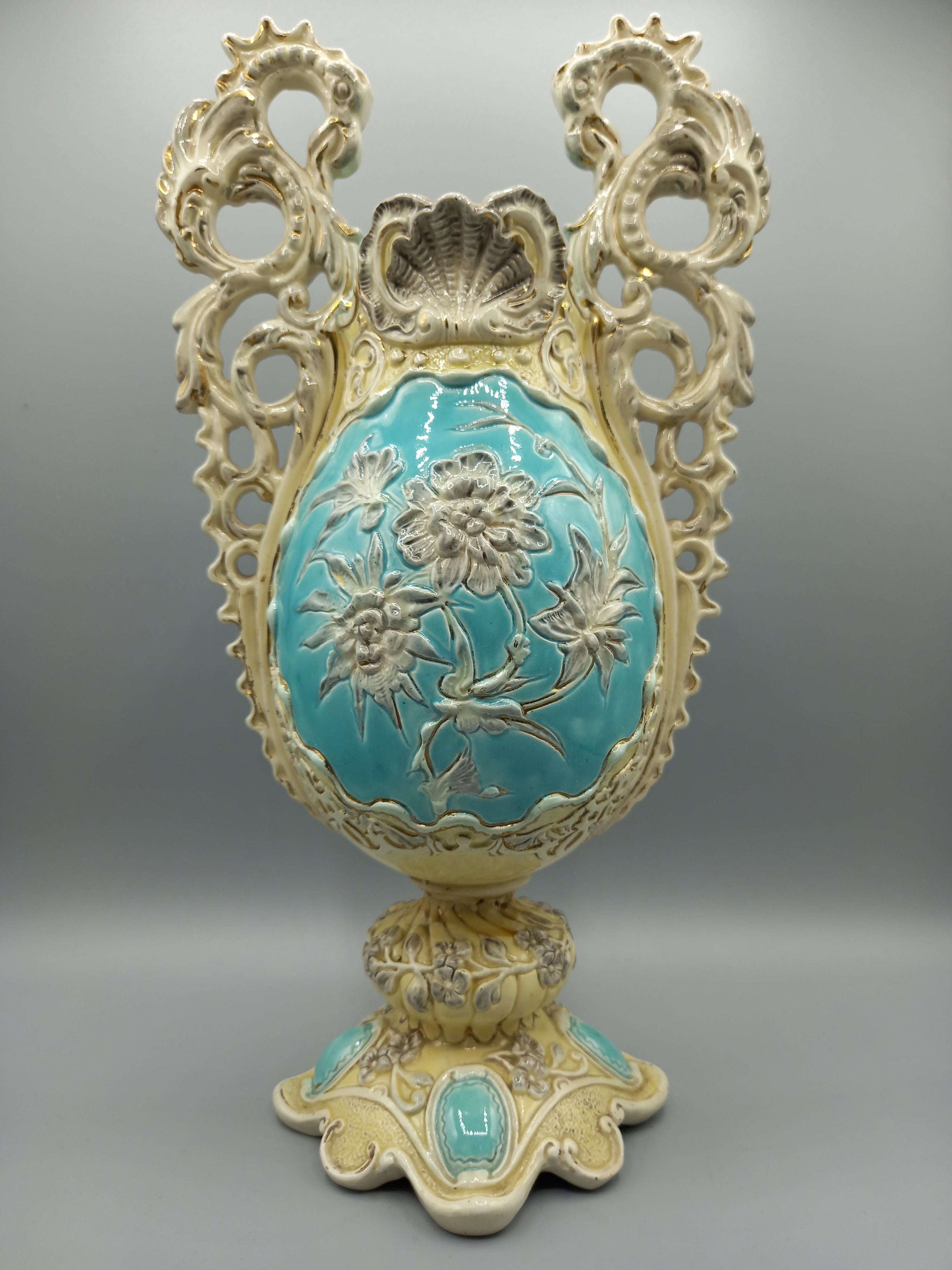 Jarron de ceramica esmaltado con detalles decorativos en tonos crema y turquesa, con relieves florales y diseño vintage ideal para decoración clásica.
