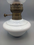 Quinque de opalina blanca para mesa con base de porcelana y detalles en latón, ideal para decoración elegante en interiores.