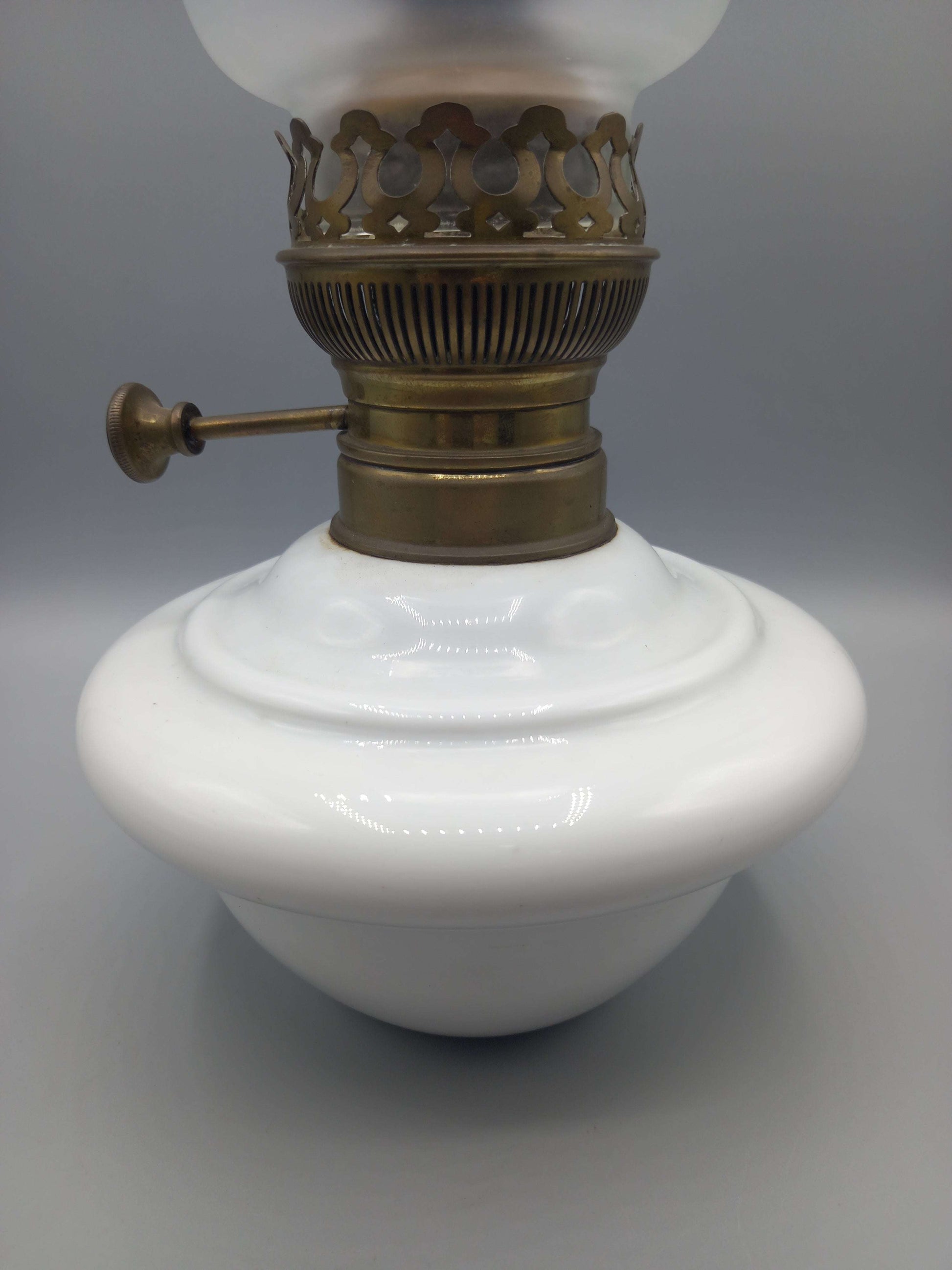 Quinque de opalina blanca para mesa con base de porcelana y detalles en latón, ideal para decoración elegante en interiores.