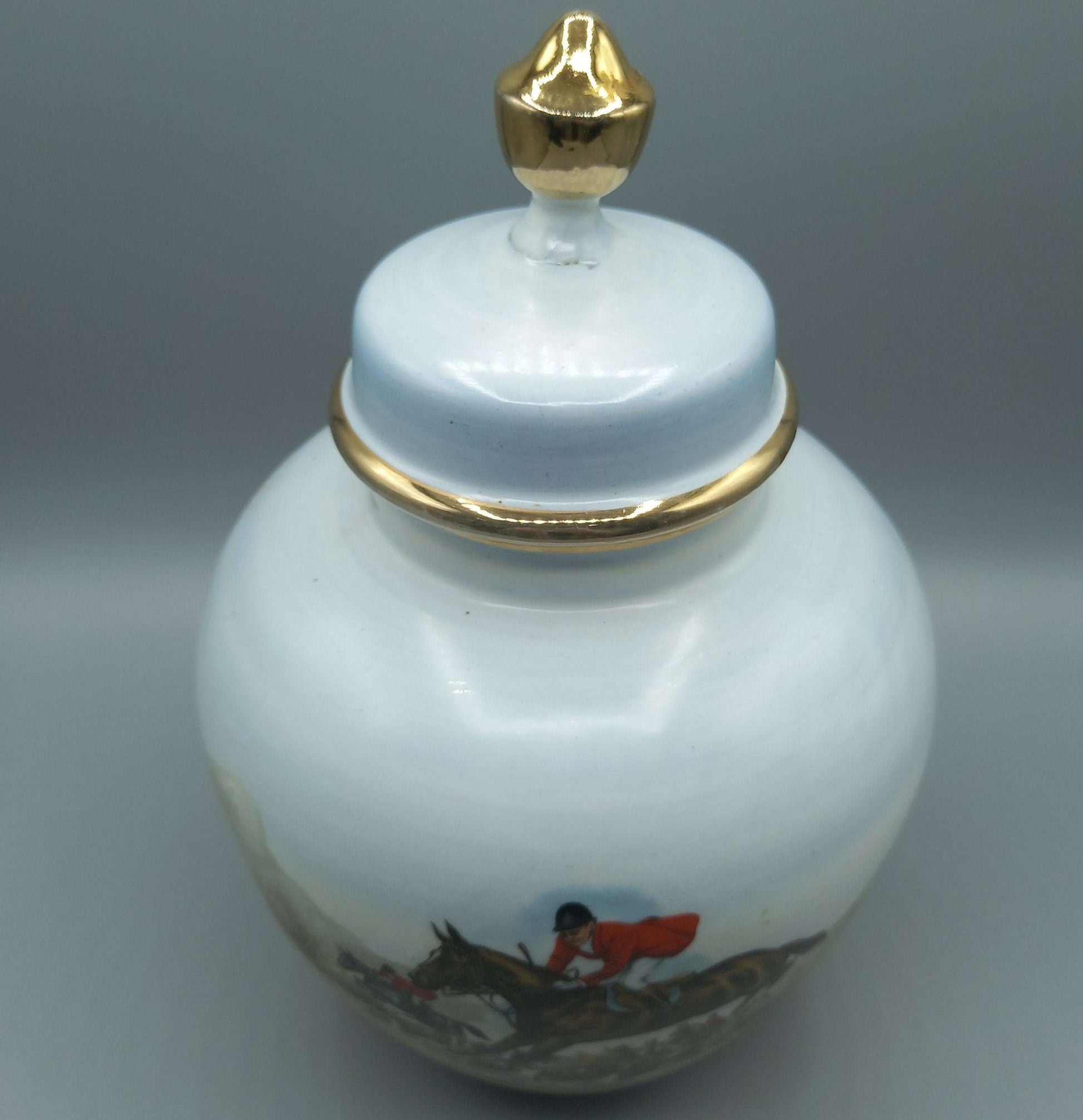 Tibor de porcelana pintado a mano con cacería inglesa, exclusivo, con tapa y detalles dorados. Ideal para decoración clásica y coleccionistas.