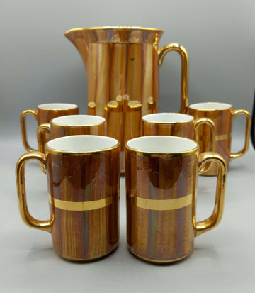 Jarra de porcelana San Claudio con acabado dorado y 6 jarritas a juego, ideal para decoración clásica en el hogar. Diseño vintage para coleccionistas.