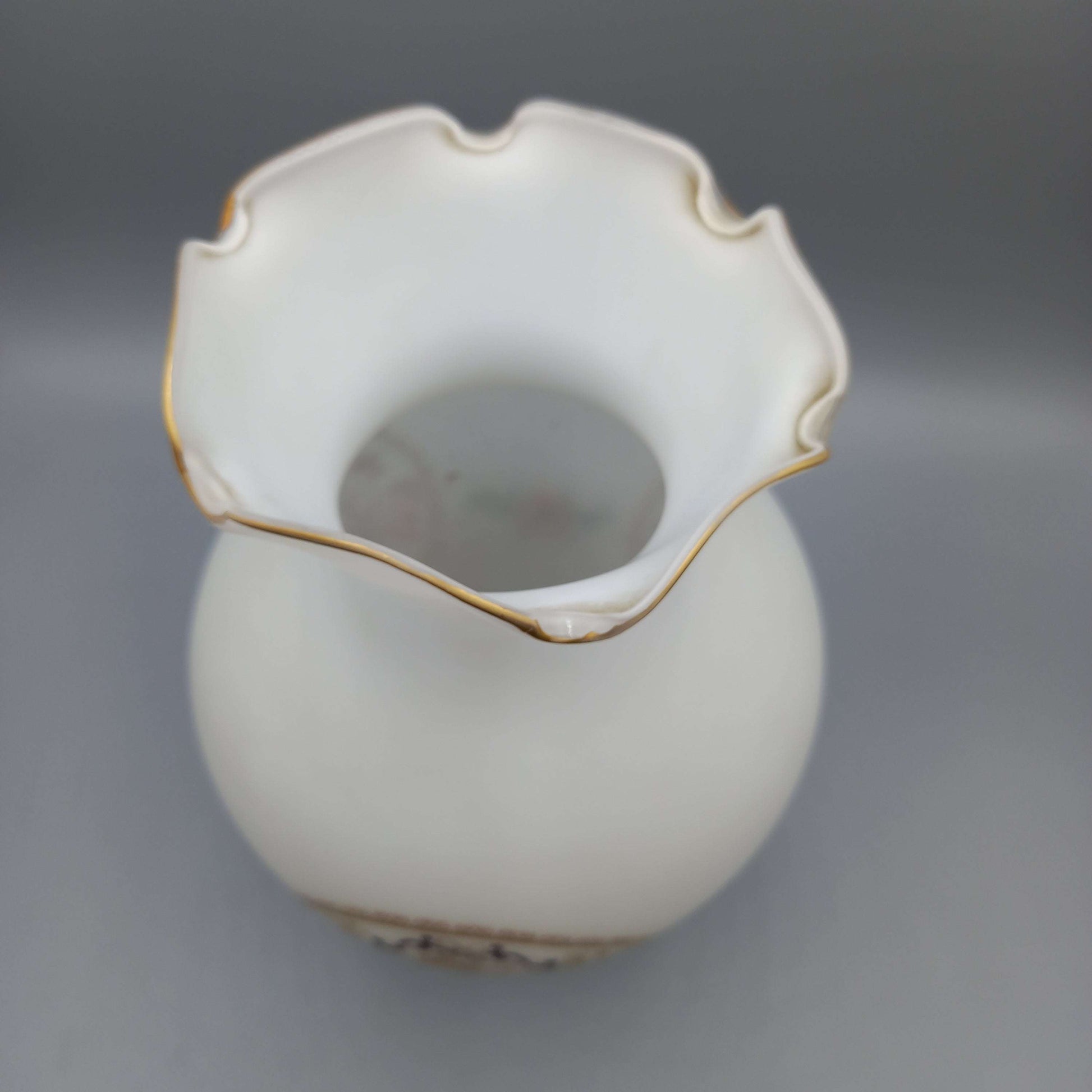 Jarrón decorativo en cristal blanco de calidad premium con borde ondulado y detalles dorados, ideal para decoración elegante de interiores.