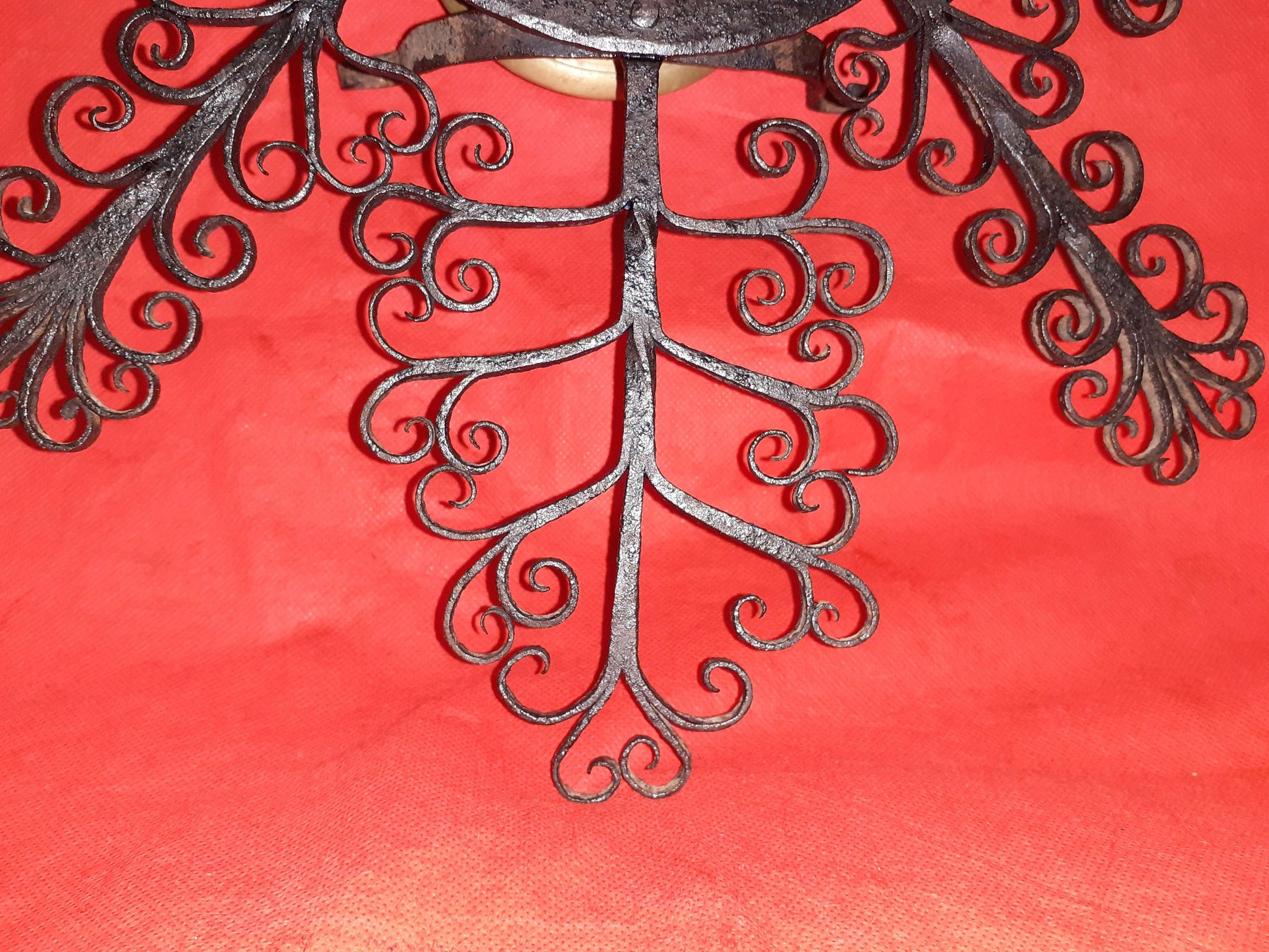 Mortero con filigranas antiguas de hierro forjado sobre fondo rojo, ideal como decoración de pared única para el hogar. Diseño ornamental exclusivo.