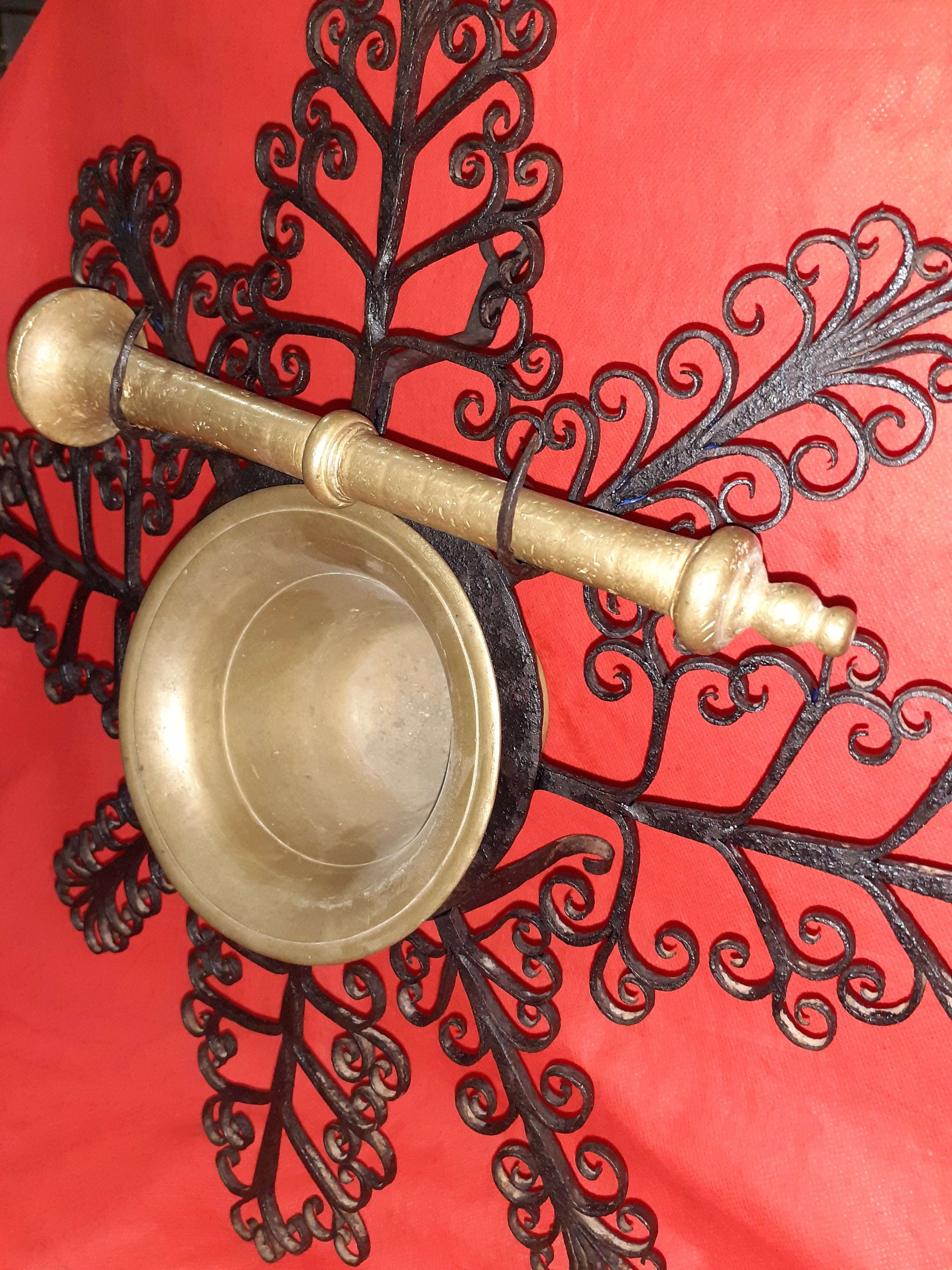 Mortero con filigranas antiguas en metal dorado montado sobre estructura de hierro forjado negro. Decoración de pared única para interiores clásicos.