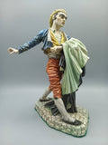 Figura Bandolero Porcelana - Algora Torero en pose dinámica, vestimenta goyesca con chaqueta azul y pantalón rojo, sobre base de piedra.